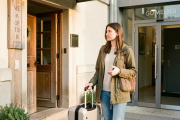 Une jeune femme voyageuse compare deux hébergements accueillants avec sa valise, dans une atmosphère lumineuse et rassurante.